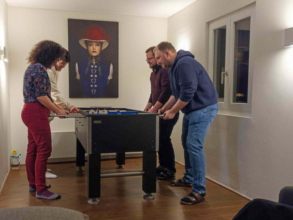 Four wetransform team members play foosball at the Saiger Lounge