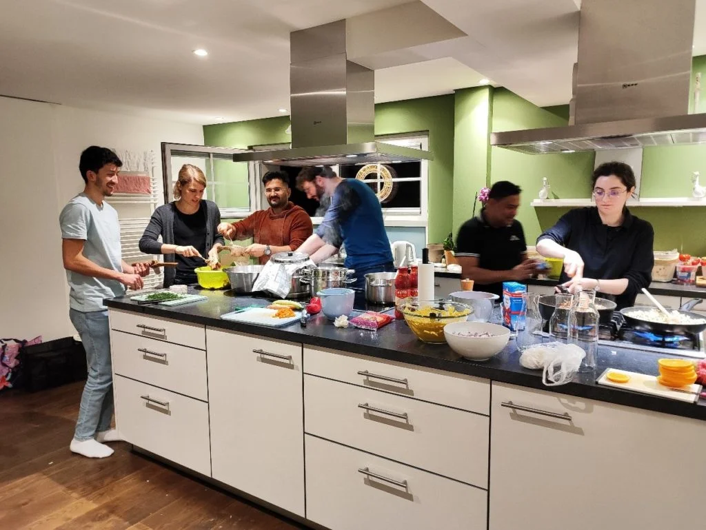 Six members of the wetransform team cook together at a large kitchen island.