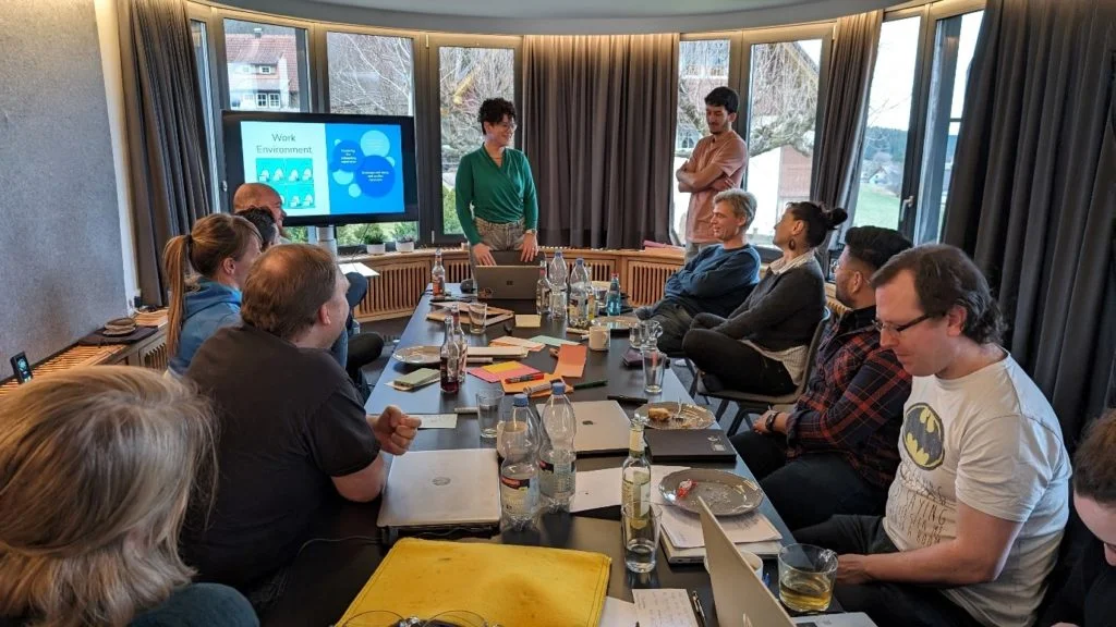 10 members of the wetransform team sit at the conference table while 2 other members present.