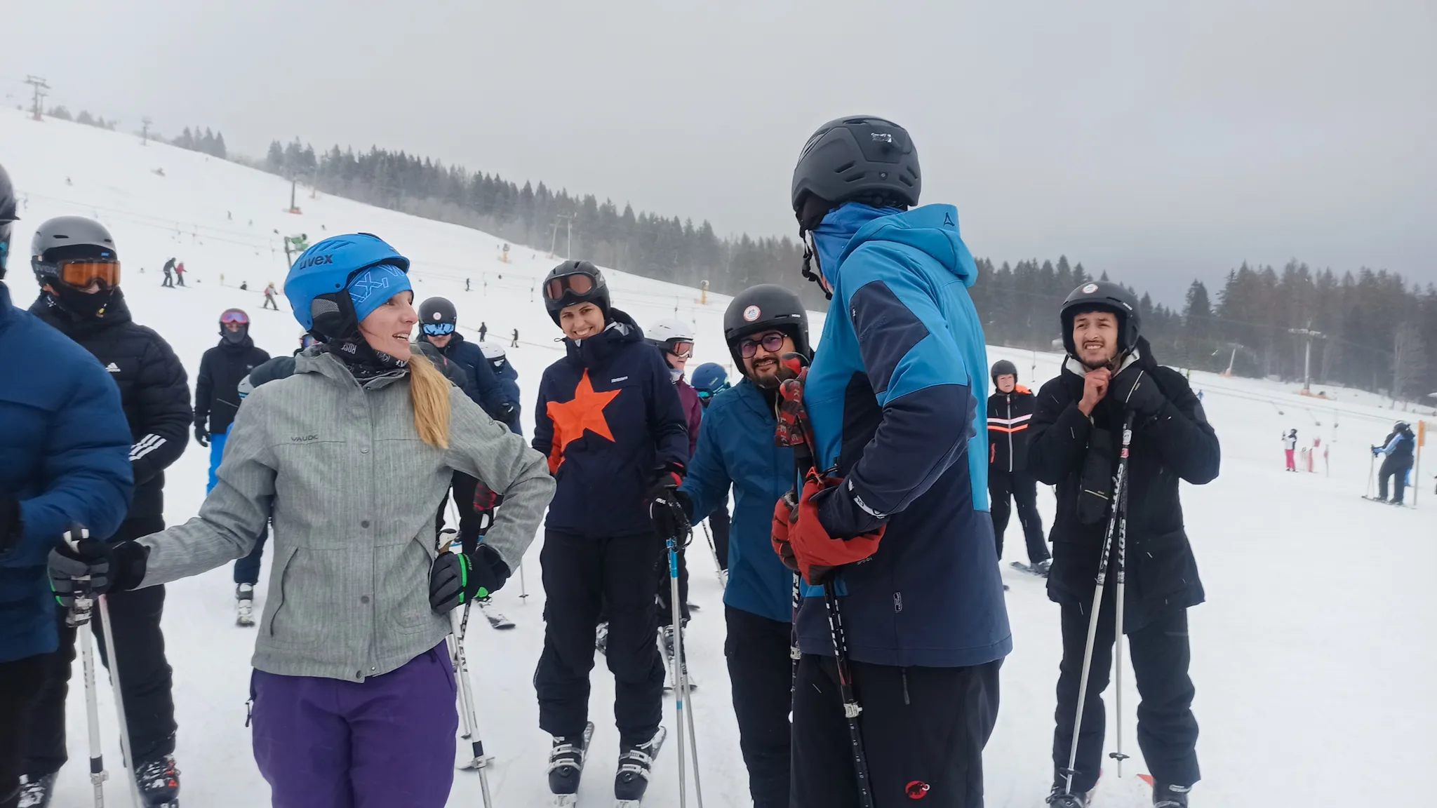Several wetransform team members sporting ski gear on a snowy slope. Franziska stands to the left, a hand on her hip. In the centre, Anna and Kapil grin at the camera. To the right, Morchid is fastening his helmet. Thorsten has his back to the camera and appears to be giving the others instructions.