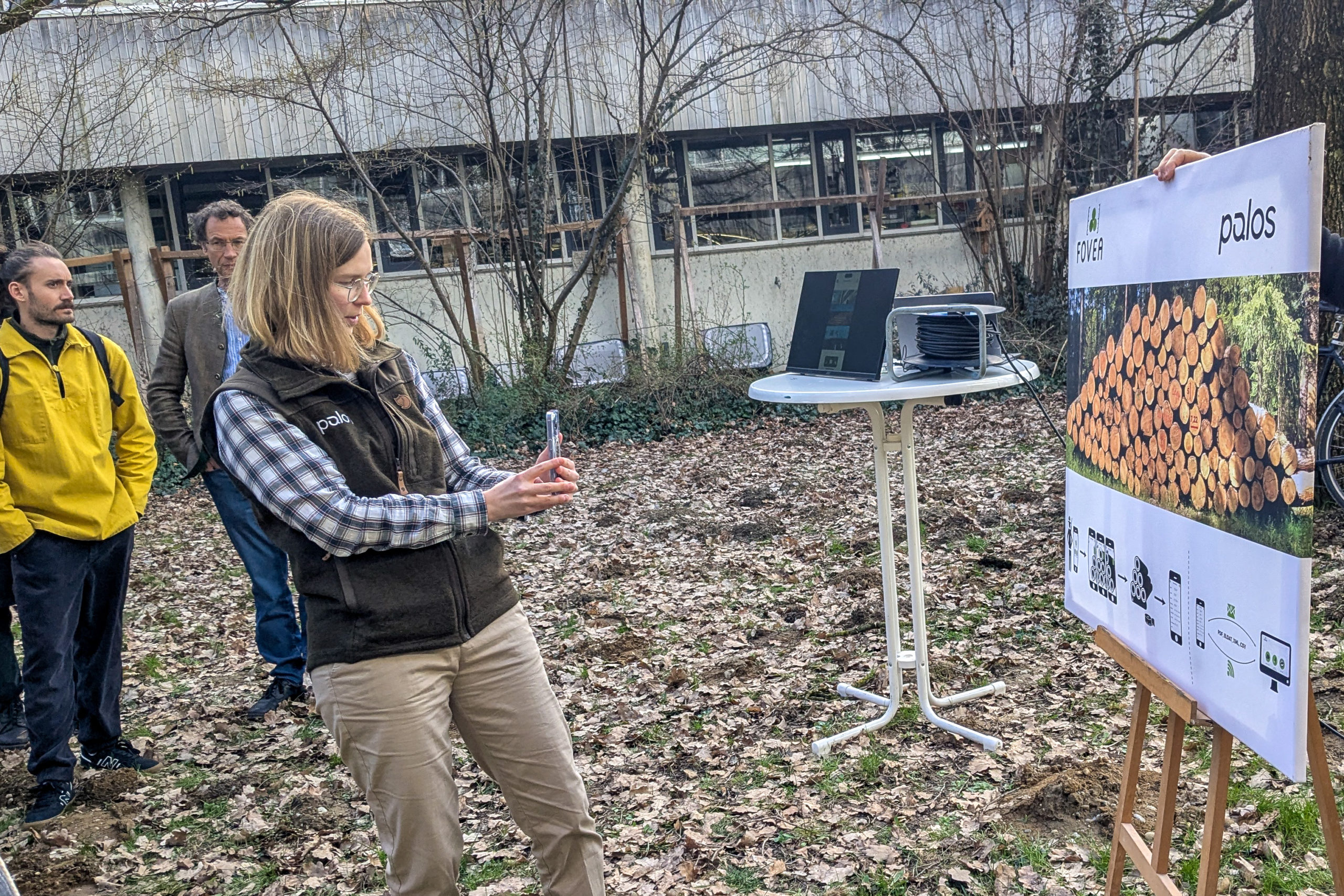 Ina Wilken of palos GmbH shows off smartphone-based forestry software FOVEA by scanning the image of a log pile during an outdoor session at SmartForest 2026.