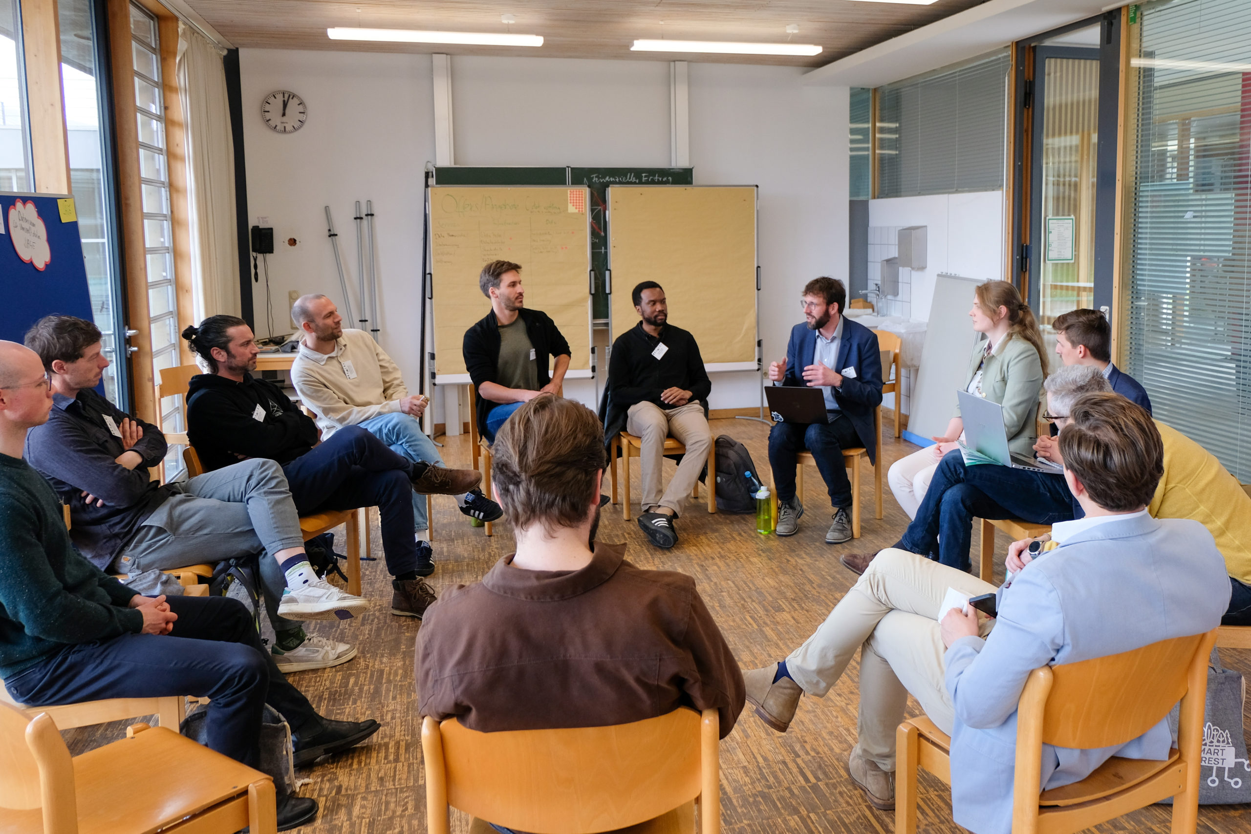 A dozen participants sit in a circle during a group discussion at the SmartForest 2026 Data Ecosystem Laboratory
