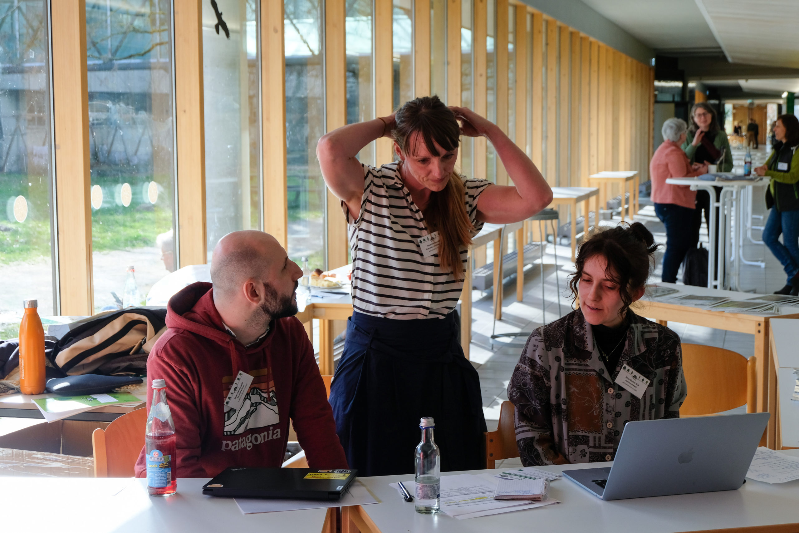 Organiser Franziska Hochenegger tying her hair whilst checking a laptop at the SmartForest 2026 reception desk, with wetransform colleagues Ronald Kilian and Ramona Resch nearby
