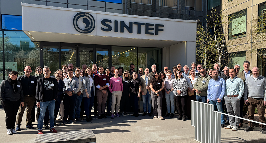 Group photograph of 45 participants of the SAGE General Assembly in Oslo, Norway, on May 7th 2026. They are gathered in a semi-circle in front of the SINTEF building, smiling at the camera on a sunny day.
