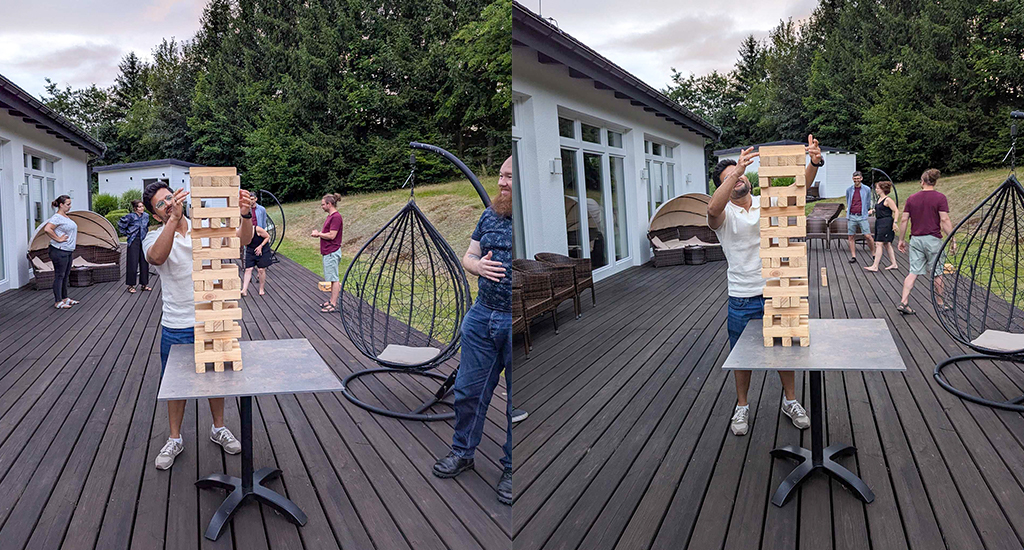 A combination of two photos where Kapil and John have built an impressively tall Jenga tower on a table outdoors. Kapil takes out a block and places it on top, while other team members play a different game in the background.